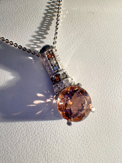 Sterling silver pendant necklace with a simulated diaspore center stone and moissanite and sapphire accents.