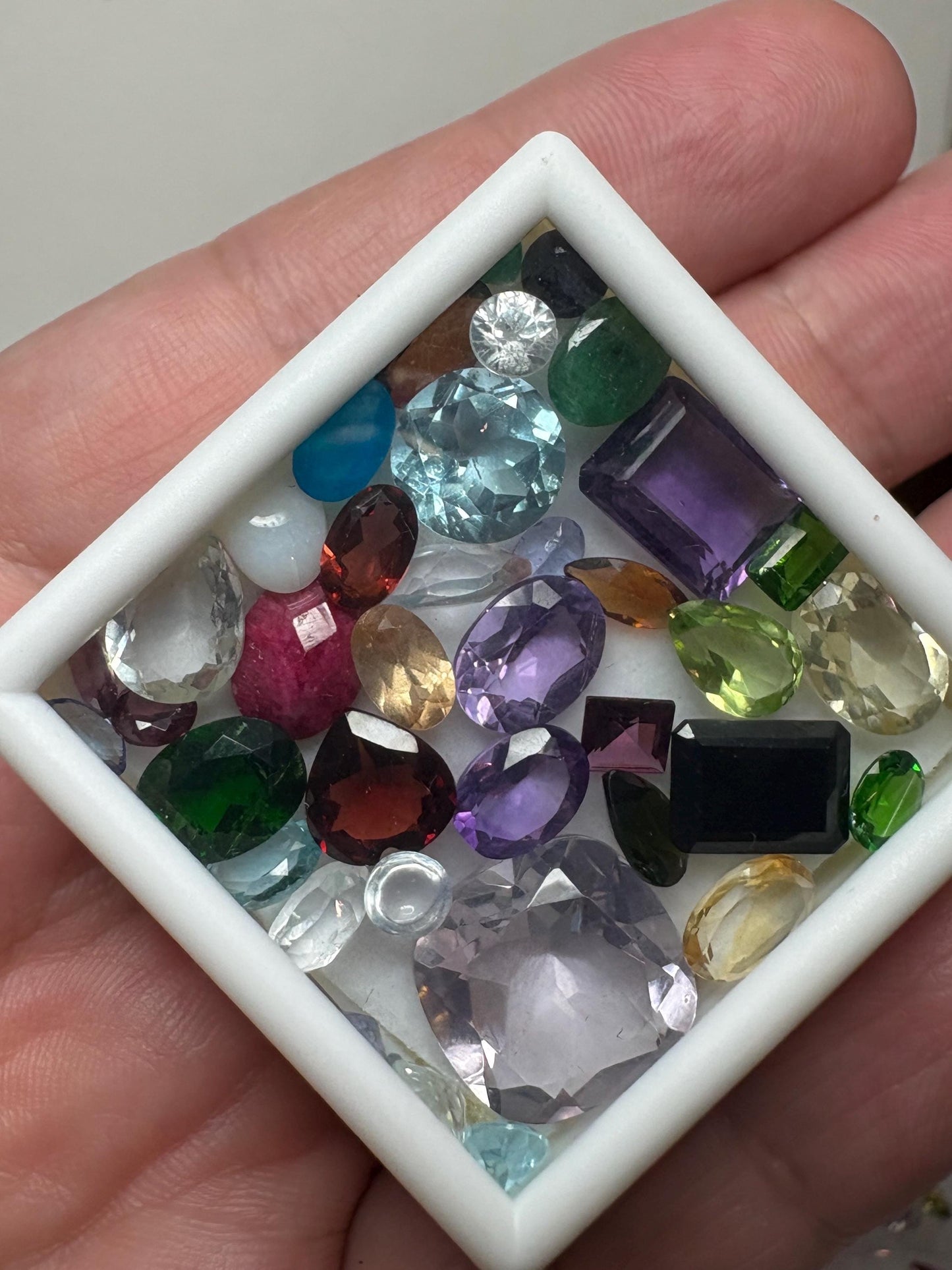 A collection of faceted and cabochon gemstones in various colors and shapes.