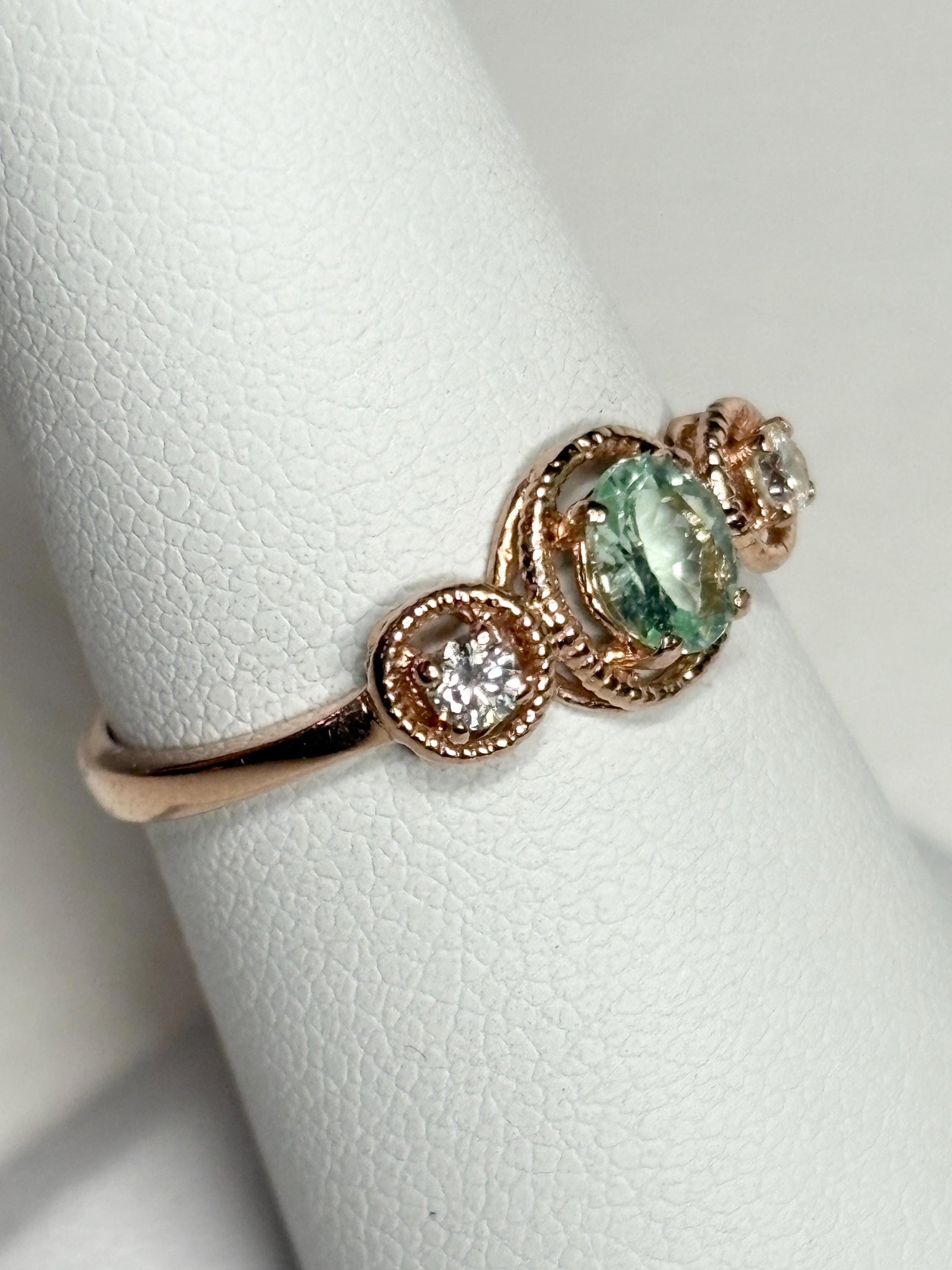 A rose gold ring with a mint green tourmaline and two diamonds.