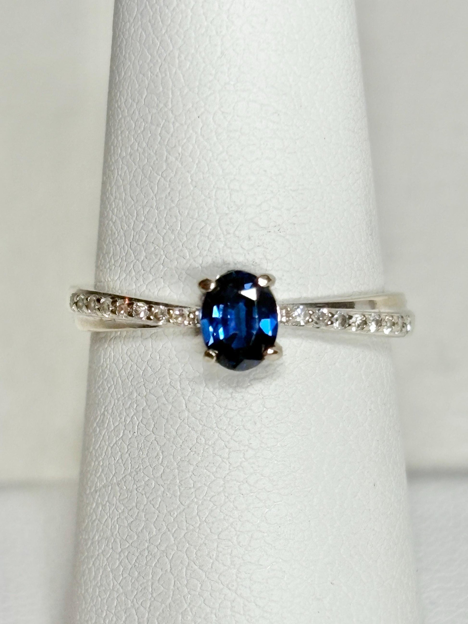 Oval blue sapphire and diamond crossover band ring in 10k gold.