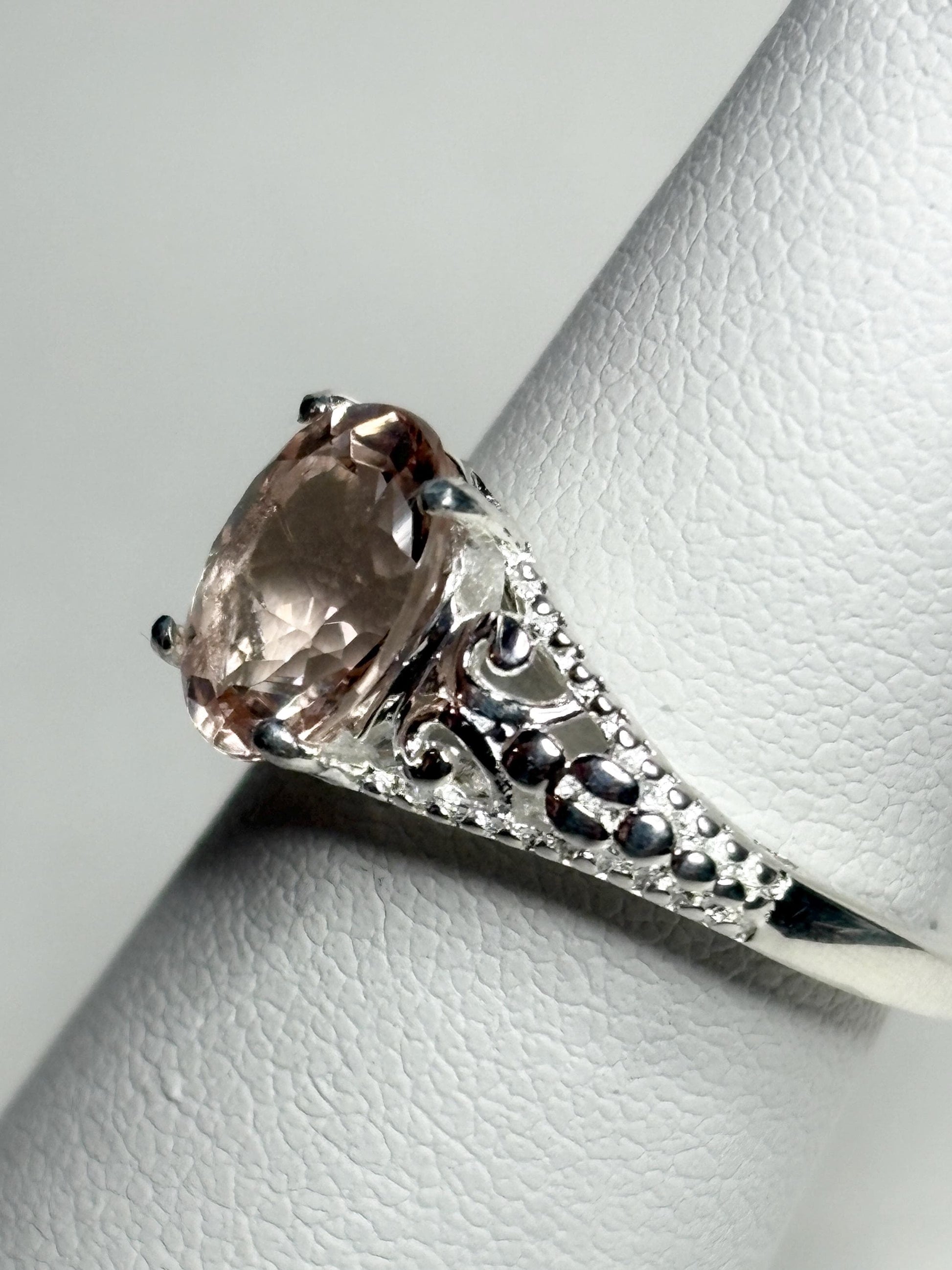 Sterling silver ring with a pink morganite gemstone and ornate detailing.