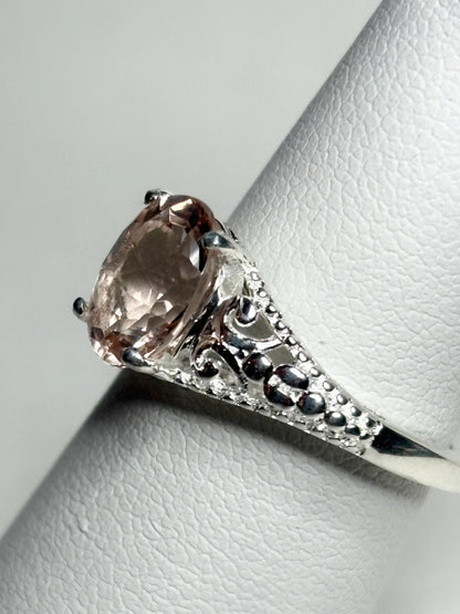 Sterling silver ring with a pink morganite gemstone and ornate detailing.