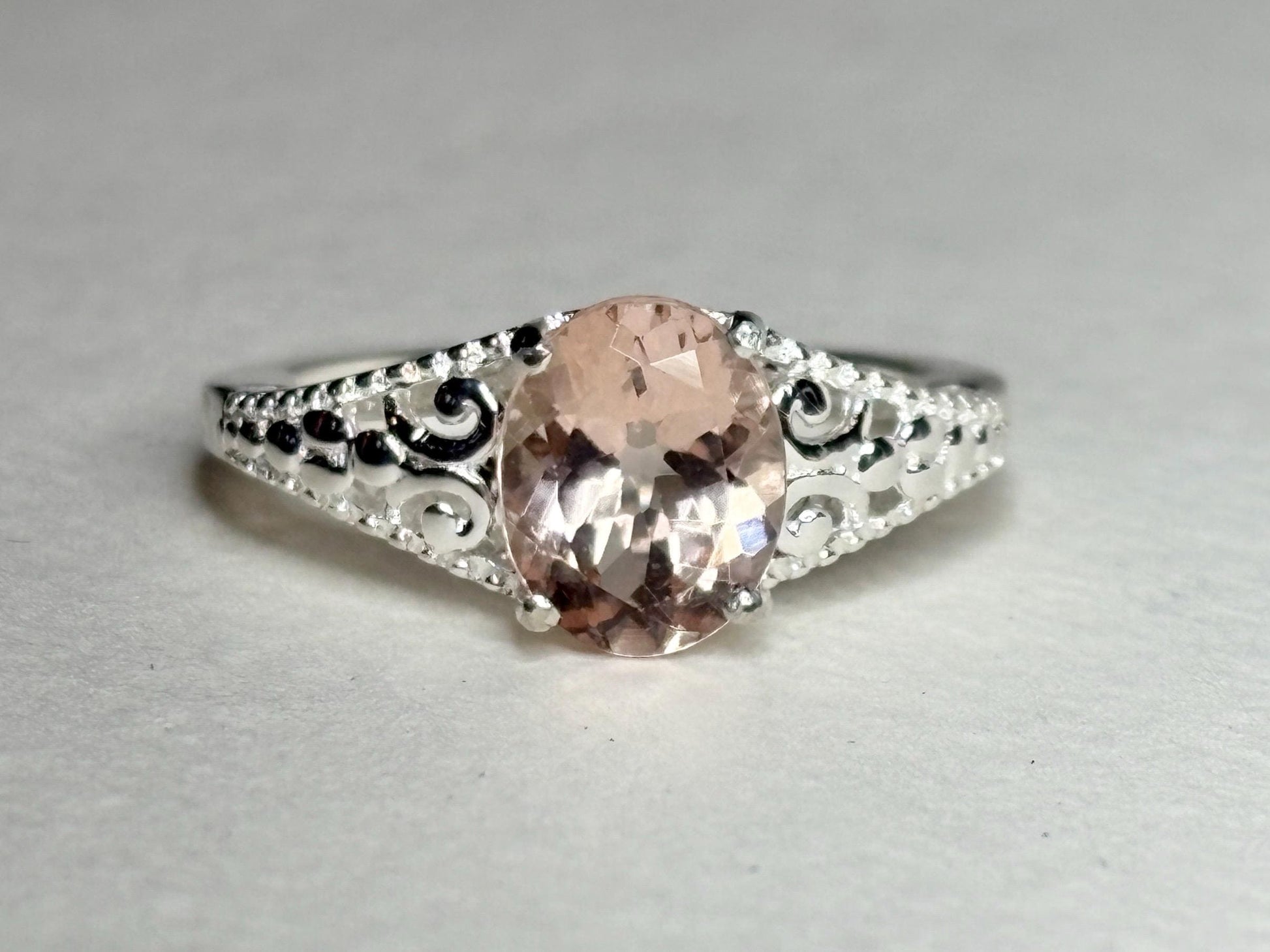 Sterling silver ring with an oval pink morganite and ornate detailing.