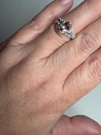 Sterling silver ring with a soft pink oval morganite and ornate details.
