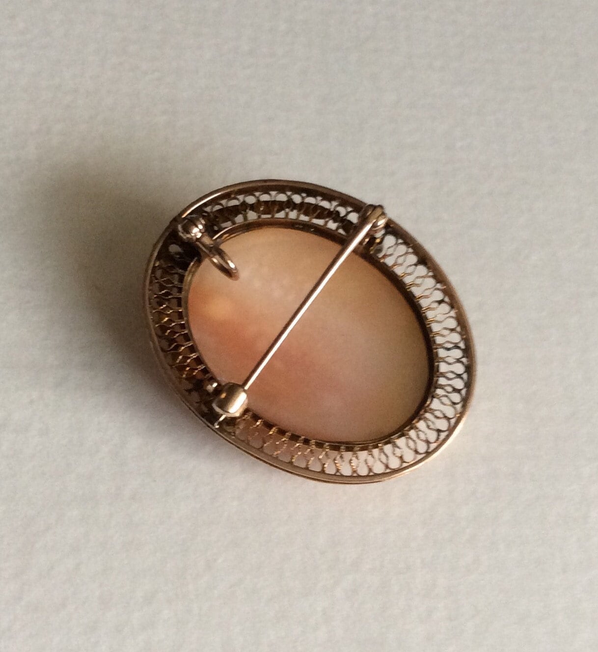 Oval cameo brooch pendant with a detailed carving of a woman's profile in a gold filigree setting.